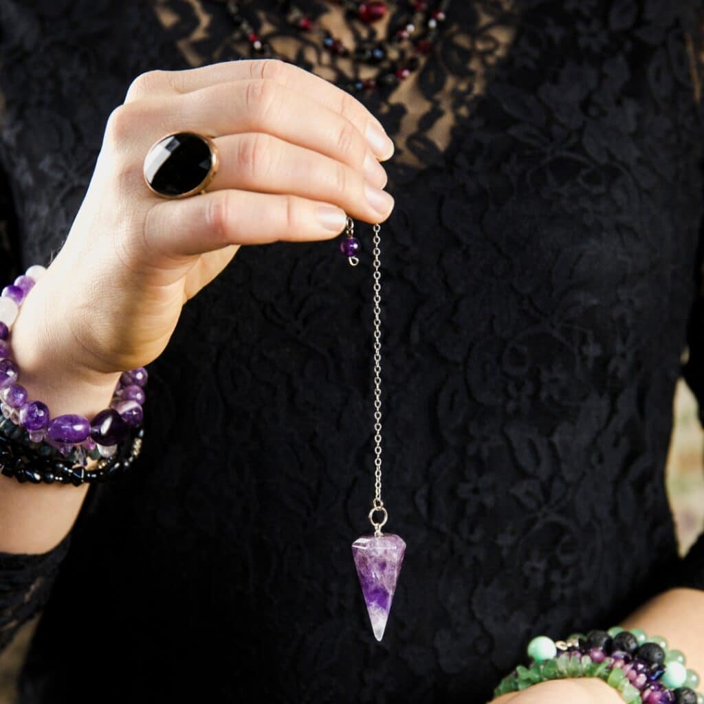 main qui tient un pendule violet