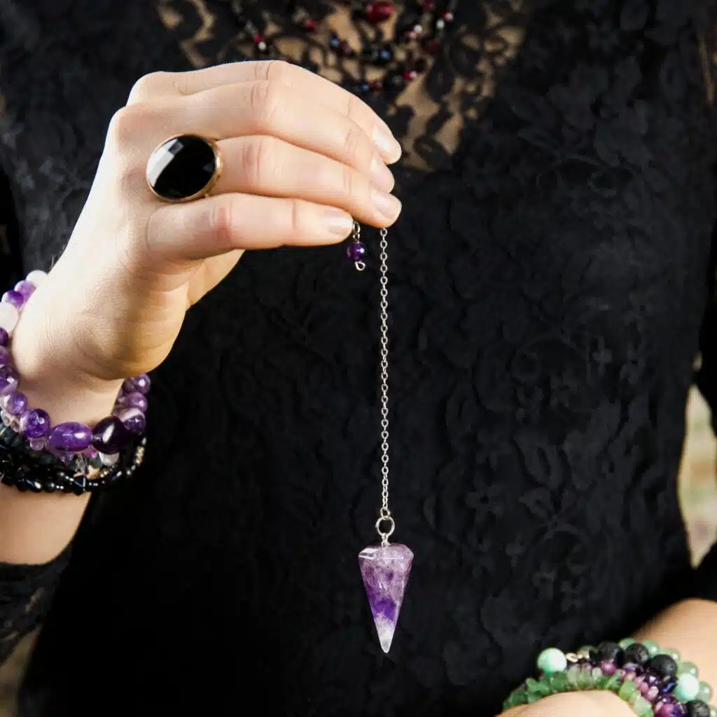 main qui tient un pendule violet