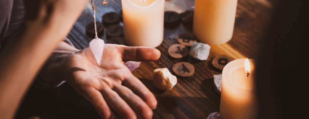 Main qui tient un pendule au dessus de la paume de la main au dessus d'une table