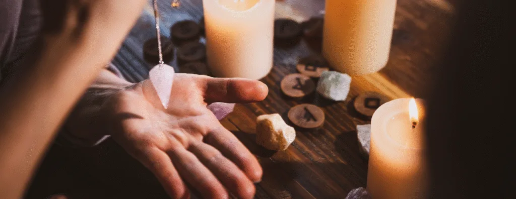 Main qui tient un pendule au dessus de la paume de la main au dessus d'une table