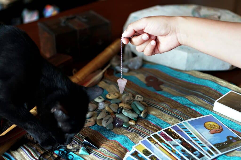 Pendule divinatoire posé sur une table avec des cartes, prêt pour une séance de questions