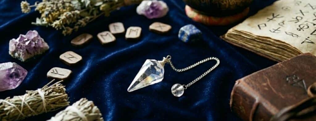 photographie d'un pendule posé sur un drap bleu et des cailloux