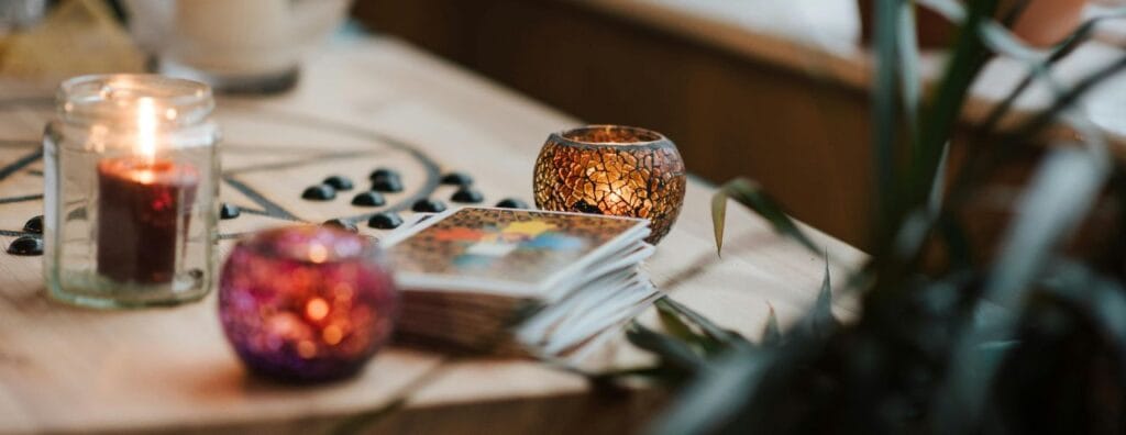 paquet de carte de tarot posé sur une table avec des bougies