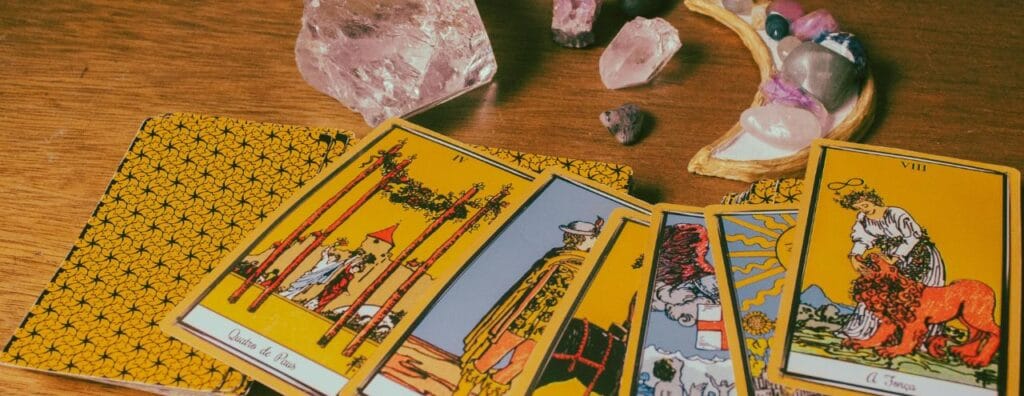 Carte de tarot disposées en arc de cercle sur une table en bois avec des pierres