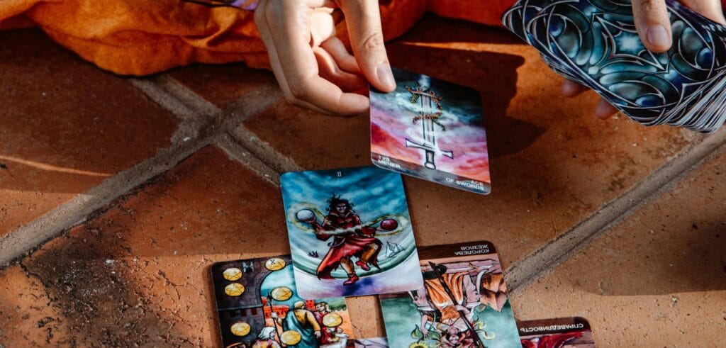 Femme qui tient une carte de tarot et qui la pose au sol à côté d'un deck de tarot de marseille